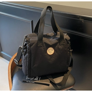 Macro detail of black nylon tote bag featuring drawstring sides and fashion logo patch