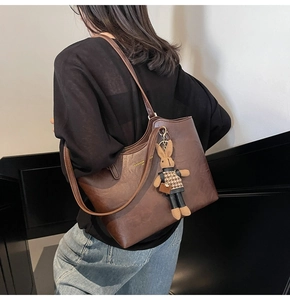 Detail of vintage dark brown tote bag with gold logo and stylish rabbit charm accessory
