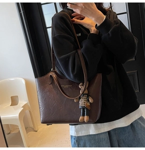 Detail of dark brown leather tote with dual straps and stylish rabbit doll charm