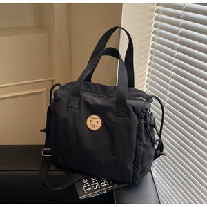 Macro shot of black nylon tote bag with drawstring details and bear leather patch