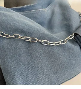 Detail of light blue denim fabric with silver chain strap on this casual tote bag