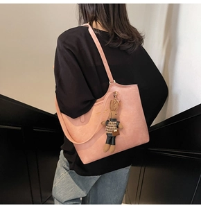 Close-up of pink faux leather tote bag with rabbit charm and metallic logo detail