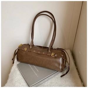 Détail du sac baguette vintage marron avec boucles dorées et glands en cuir élégants