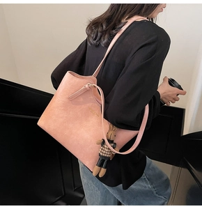 Detailed texture of pink faux leather tote bag with gold lettering and rabbit charm