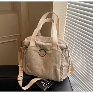 Detail of beige canvas tote bag with adjustable strap and circular bear logo patch