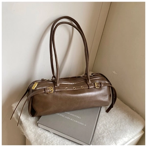 Détail du sac baguette marron rétro avec boucles dorées sur polaire blanche douce