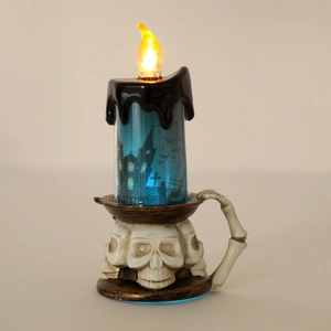 Dettaglio candela LED di Halloween con base a teschio e glitter blu su sfondo neutro