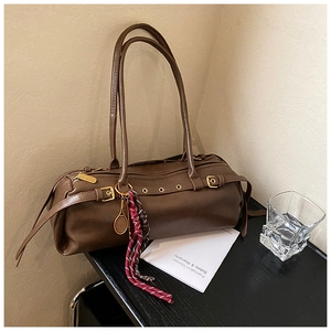 Détail du sac baguette marron vintage avec boucle dorée et pendentif de tennis chic