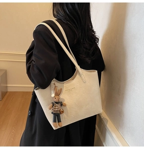 Detail of off-white leather tote bag with a cute brown bunny charm and printed text