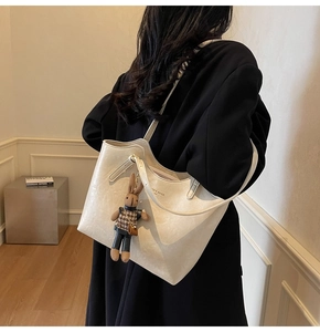 Detail of cream oversized tote bag featuring vintage leather texture and rabbit charm