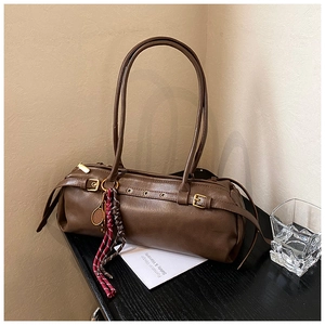 Détail du sac baguette vintage marron avec boucles dorées et pendentif de tennis