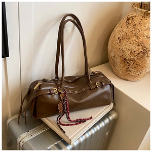 Vue détaillée du sac baguette marron rétro avec œillets sur valise argentée