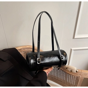 Detail of black cylindrical barrel bag showing glossy leather texture and silver hardware