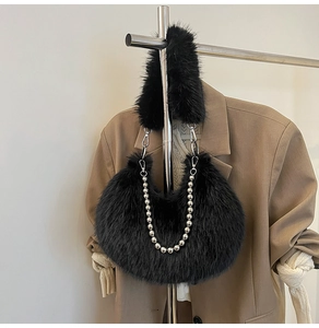 Detail of black faux fur hobo bag with silver beaded chain on warm blazer background