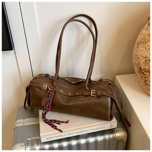 Détail du sac cylindre vintage marron avec breloque raquette de tennis et pompon