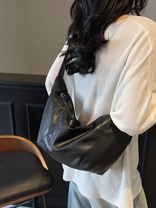 Minimalist black leather slouchy shoulder bag with diagonal stitching on model