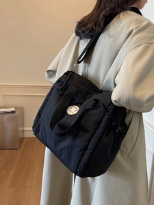 Black quilted puffer tote bag with bear patch shown on a model in a minimalist setting