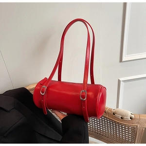 Close-up of a red cylindrical leather bag with double silver-buckle straps and smooth finish