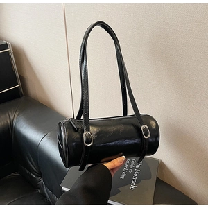 Detail of a black glossy leather barrel bag with silver buckle and vintage texture