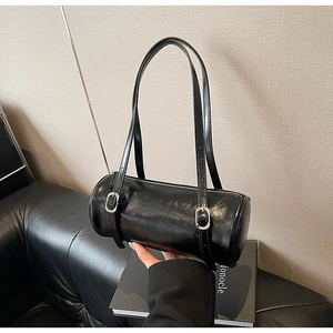 Detail of a black cylinder shoulder bag in glossy leather with silver buckles