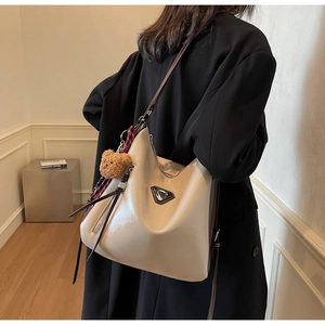 Detail of hobo bucket bag in beige patent leather with plush bear and metal logo