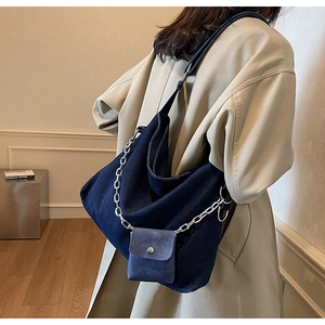 Detailed close-up of blue denim hobo bag with silver chain and a mini square pouch