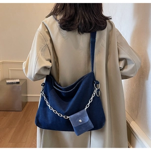 Detail of deep blue denim tote bag featuring a silver metal chain and detachable coin purse