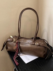 Sac baguette cylindrique marron avec longues bretelles et pendentif raquette de tennis