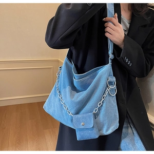 Detailed shot of large light blue denim hobo bag with metal chain and matching mini pouch
