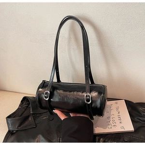 Detail of black cylinder barrel bag in glossy patent leather with silver buckle strap