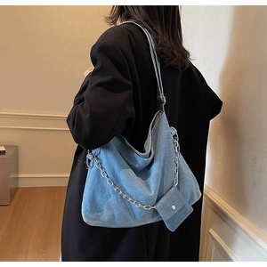 Close-up of light blue denim tote bag with silver chain and matching mini pouch