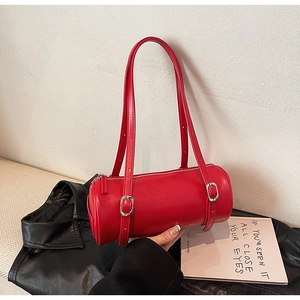 Detail of red cylindrical shoulder bag with adjustable silver buckle straps