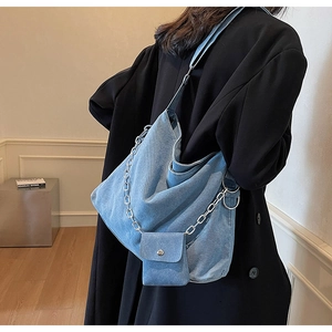 Detail of blue denim hobo bag with silver chain and mini pouch on black coat