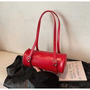 Detail of red barrel bag with adjustable silver buckle straps on black leather backdrop
