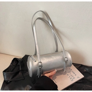 Detail of silver metallic barrel bag showing smooth texture and adjustable buckle straps