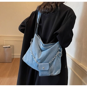 Detail of light blue denim hobo bag with silver metal chain and small square pouch