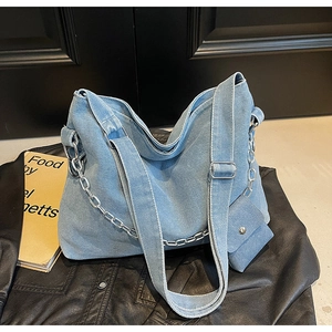Detail of light blue denim tote bag with silver chain and mini coin purse attachment