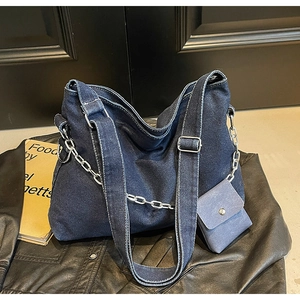 Detail of dark blue denim tote bag with silver chain, mini pouch and white contrast stitching