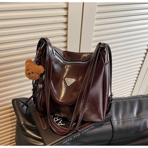 Close-up of dark brown wax leather tote with silver hardware and plush bear charm