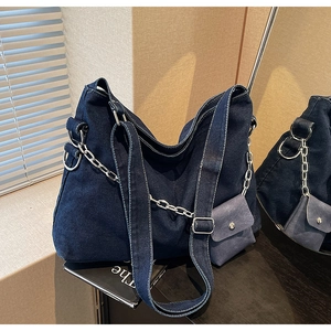 Detail of dark blue denim tote bag with silver chain and matching mini pouch on books