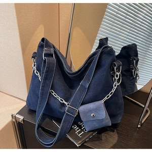 Detailed close-up of dark denim tote bag with silver metal chain and mini pouch accessory