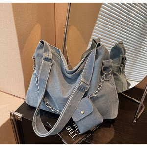 Macro detail of a light blue denim hobo tote bag with a matching small coin purse attachment