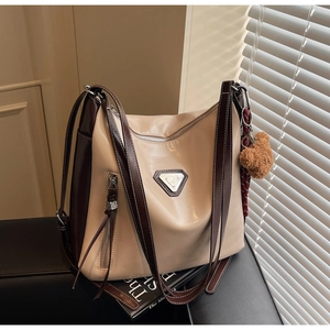Macro detail of bicolored tote bag showing metal triangle logo and fine stitching