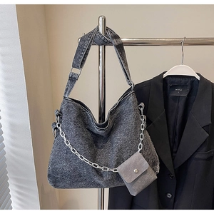 Detail of a dark gray denim hobo bag featuring silver chain and matching mini pouch
