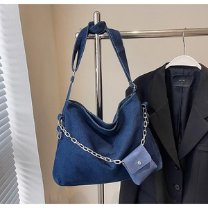 Detail of dark blue denim hobo bag with silver chunky chain and detachable mini pouch
