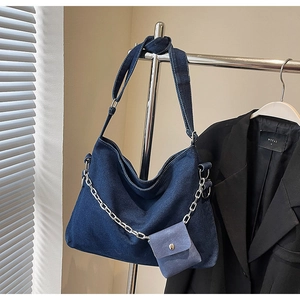 Detail of dark blue denim tote bag with silver chain and mini pouch on a metal rack