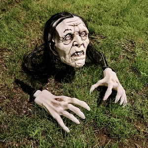 Detailed zombie skull with long hair and skeletal hands emerging from the garden grass