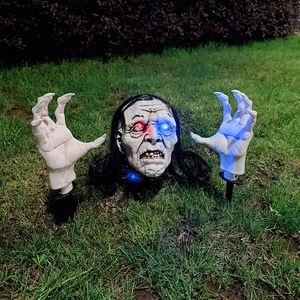 Glowing skull head and bony hands with long hair for Halloween garden decoration