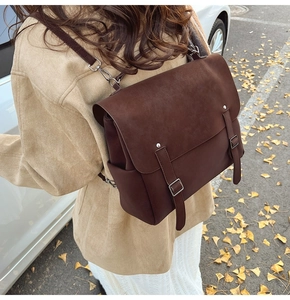 Detailed back view of a vintage dark brown frosted leather backpack in an autumn outdoor setting