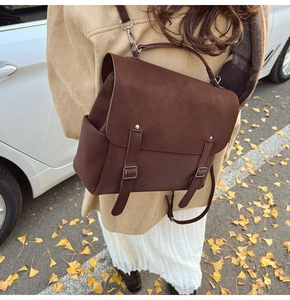 Detail of dark brown vintage backpack with matte suede texture and metal buckle straps